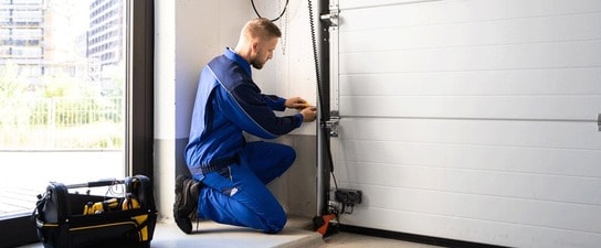 Service tech performs garage door repair at a home